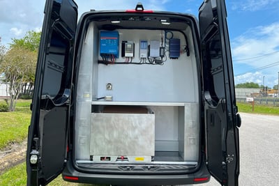 The back end of a hostage negotiation vehicle with two open doors showing storage for tactical equipment.